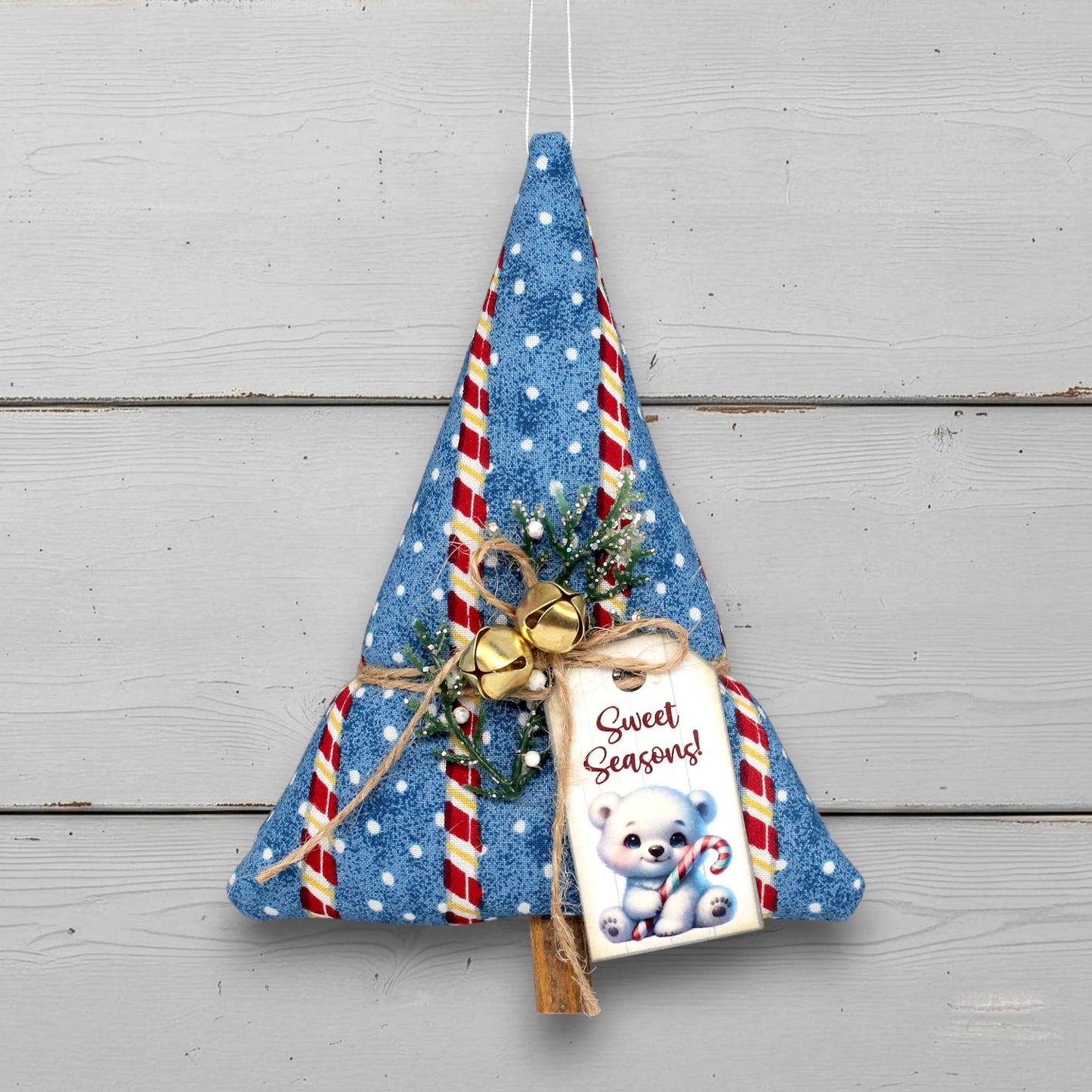 Decorative Christmas tree ornament with candy cane pattern and 'Sweet Seasons!' tag on a wooden background