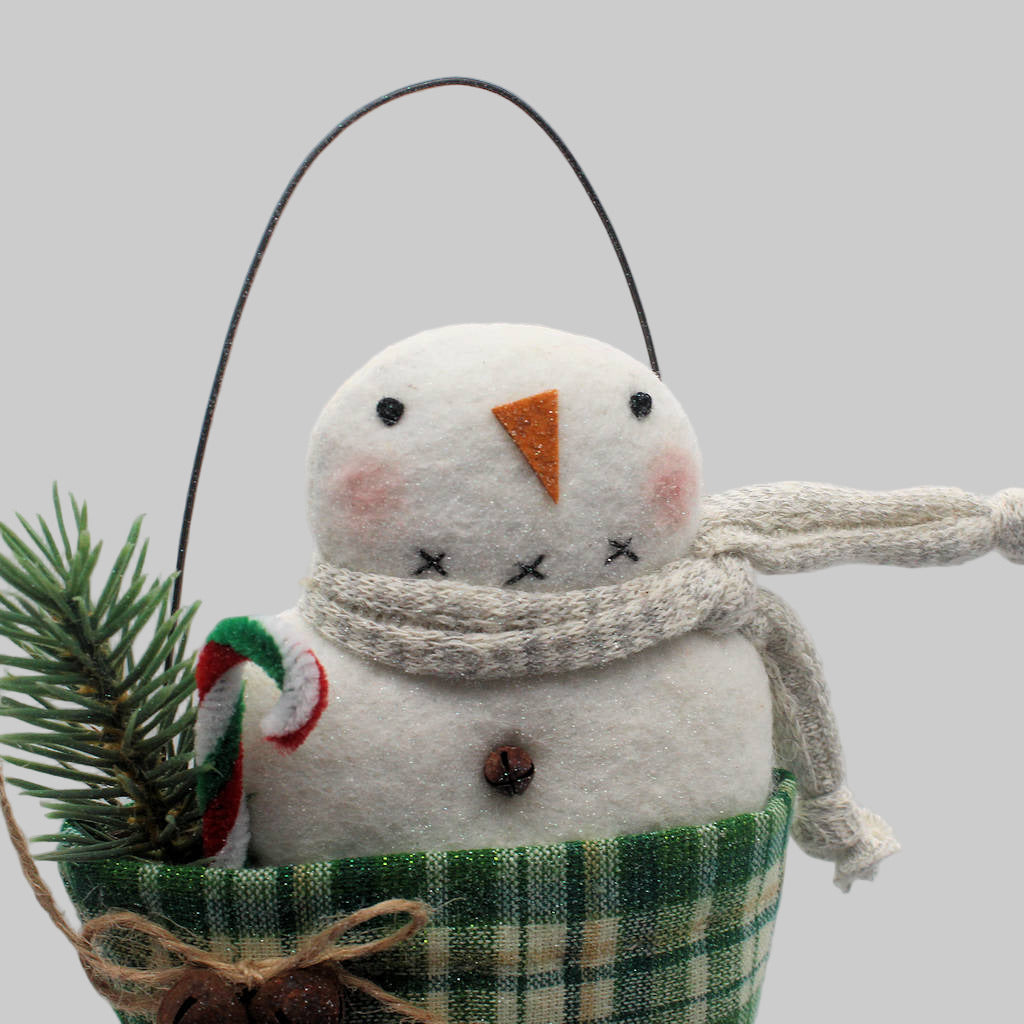 Primitive snowman ornament in a green homespun stocking with pine and a candy cane