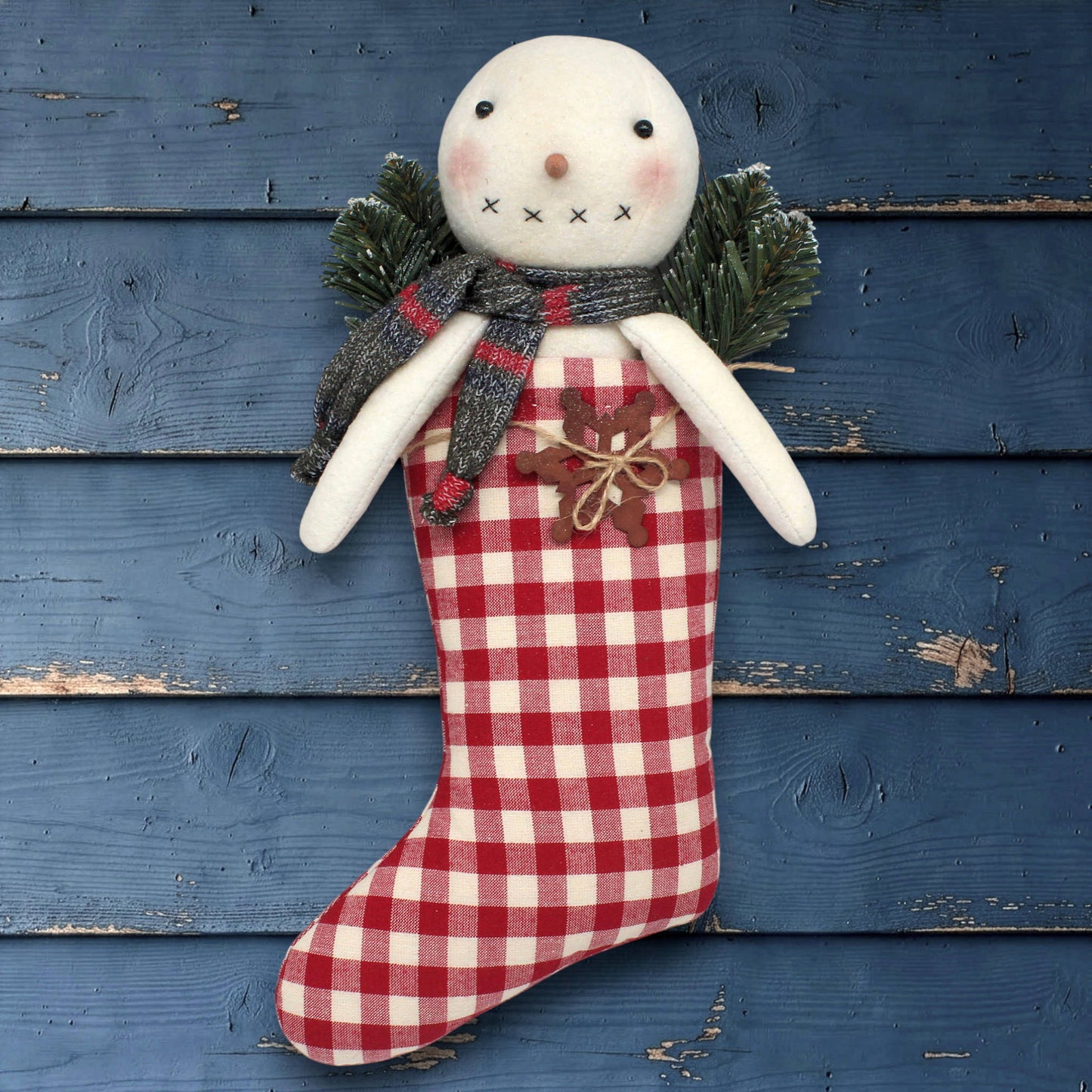 Snowman toy with a red and white checkered stocking against a blue wooden background