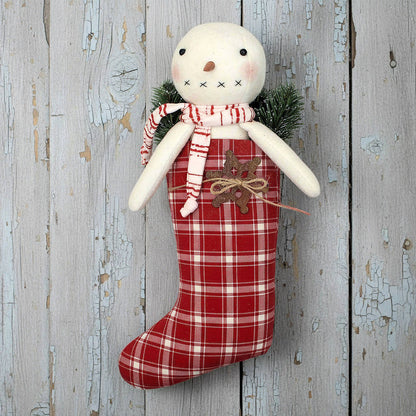 Decorative handmade snowman with a red plaid stocking on a rustic wooden background