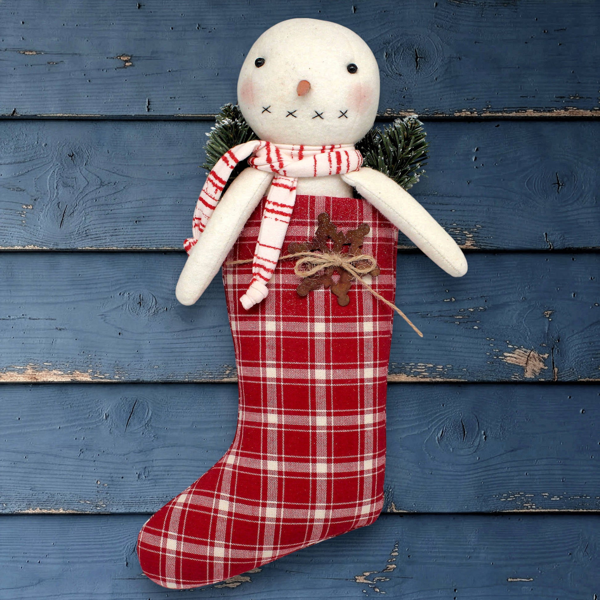 Decorative handmade snowman with a red plaid stocking on a rustic wooden background