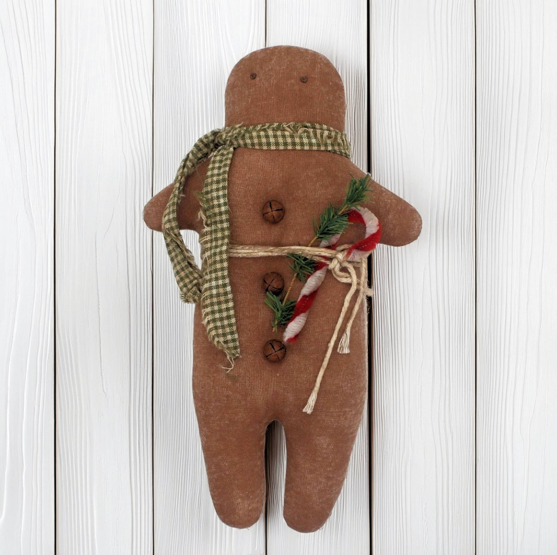 Primitive gingerbread man doll with a scarf and candy on a wooden background