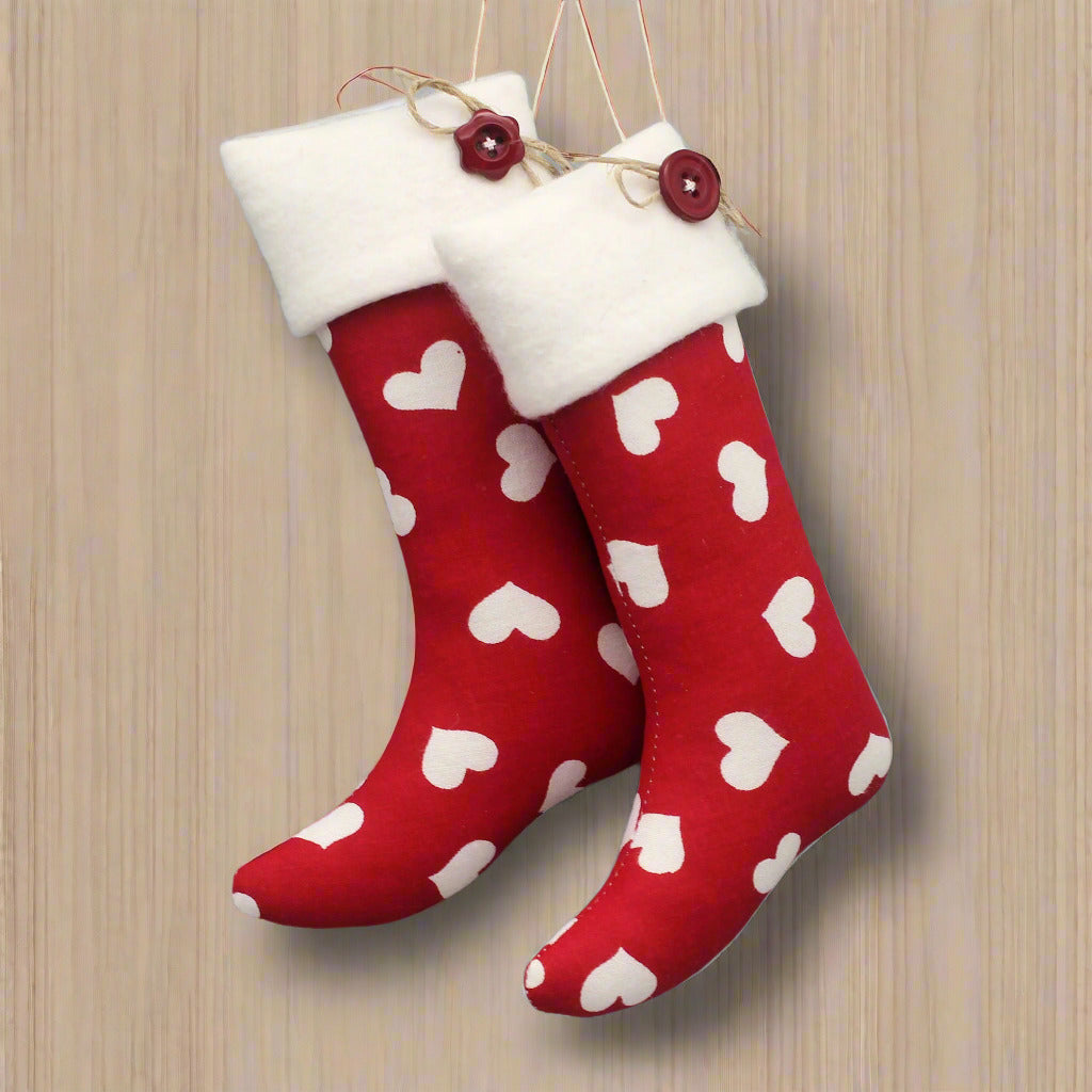 Christmas stocking ornaments with white hearts on a red background with white fleece cuffs decorated with buttons