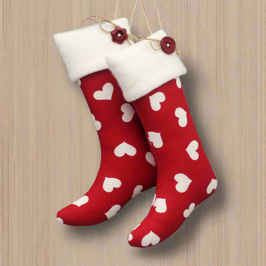 Christmas stocking ornaments with white hearts on a red background with white fleece cuffs decorated with buttons