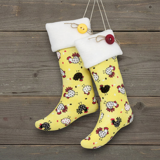 Yellow Christmas stocking ornaments with black and white chicken pattern hanging on a wooden surface