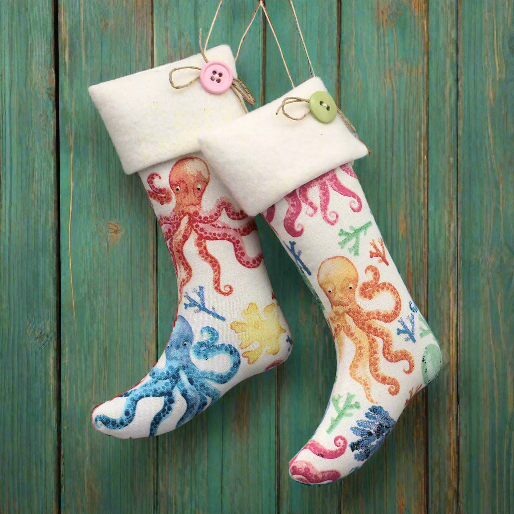 Christmas stocking ornaments with colorful octopi on a white background and white cuffs decorated with buttons