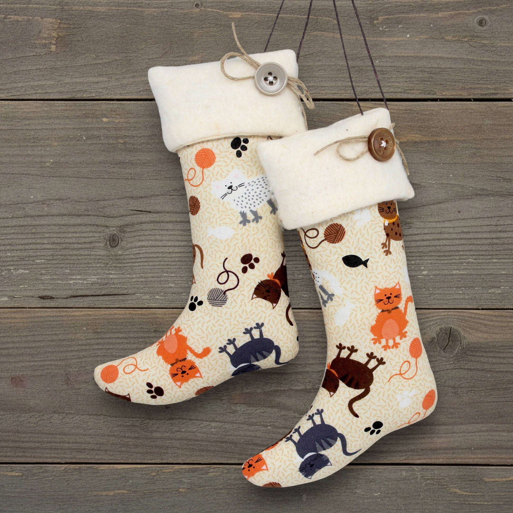 Two decorative stockings with cat and dog pet patterns on a wooden surface