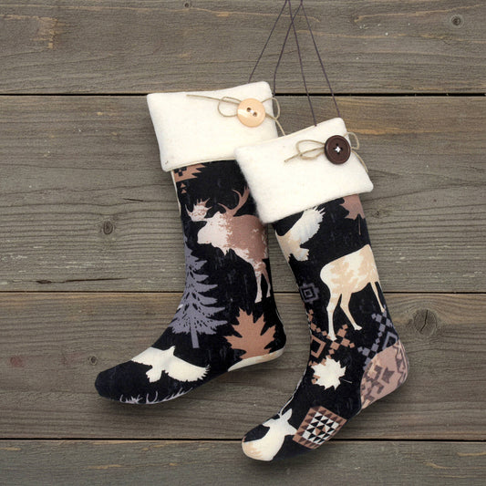 Pair of Christmas stocking ornaments with deer pattern hanging on a wooden surface