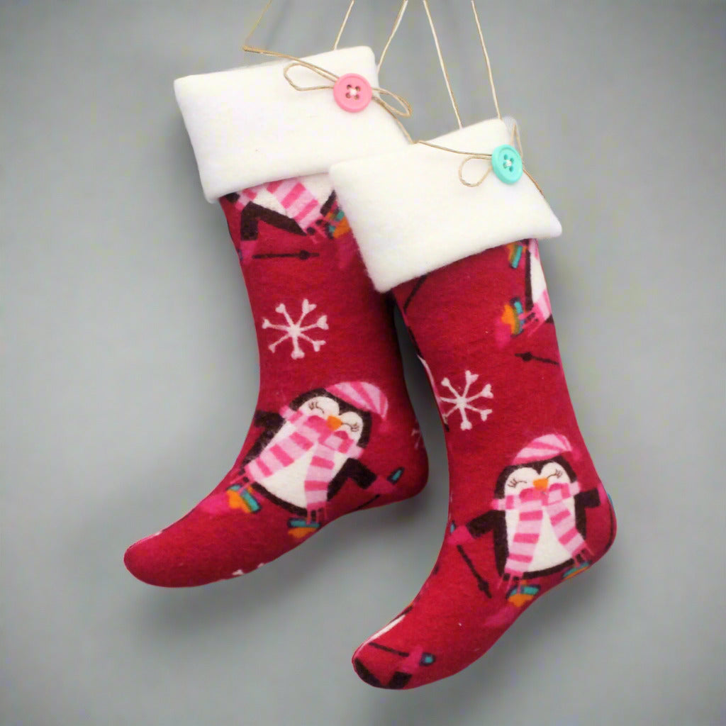 Christmas stocking ornaments with cute penguins on a dark pink background with white cuffs decorated with buttons