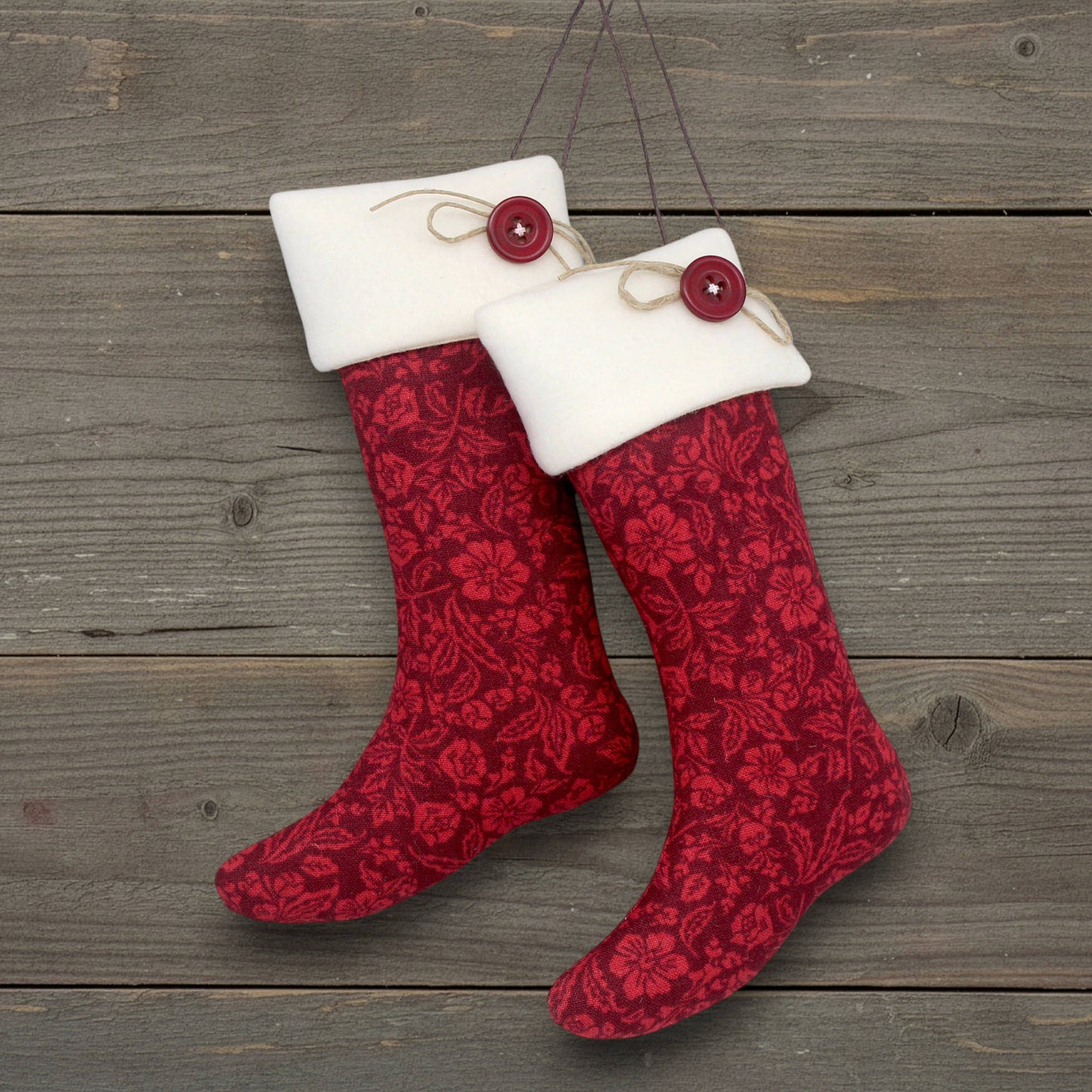 Red patterned Christmas stocking ornaments with white cuffs and red buttons on a wooden surface