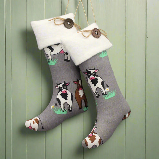 Christmas stocking ornaments with farmhouse cows on a gray background with white cuffs decorated with buttons