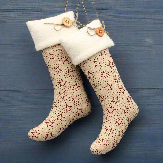 Farmhouse style Christmas stocking ornament with burgundy stars on a tan fabric background with white fleece cuffs decorated with buttons