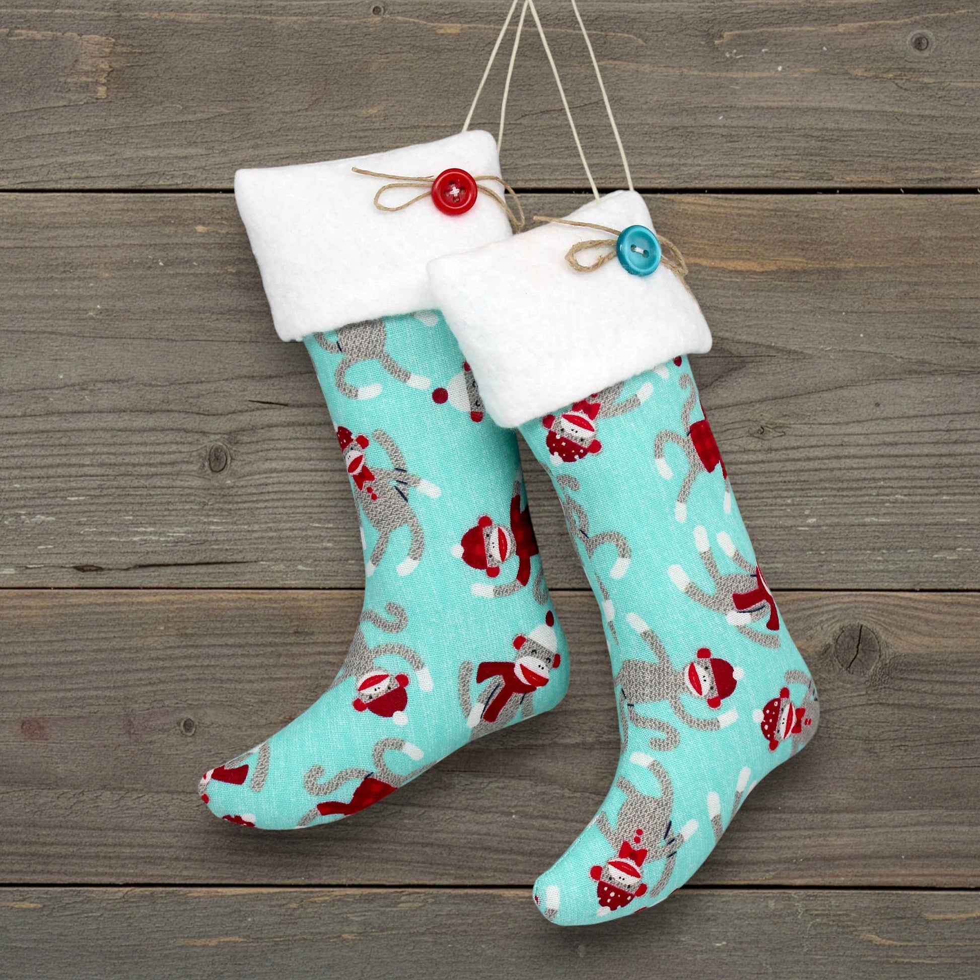 Pair of Christmas stocking ornaments with a sock monkey pattern on a greenish blue background