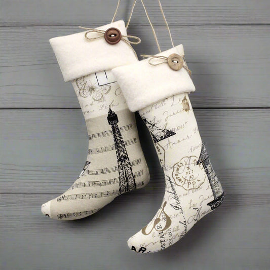 Pair of decorative stockings with musical notes and Eiffel Tower design on a wooden surface.