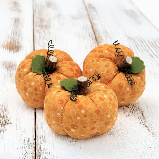 Three decorative pumpkins with polka dot patterns on a wooden surface