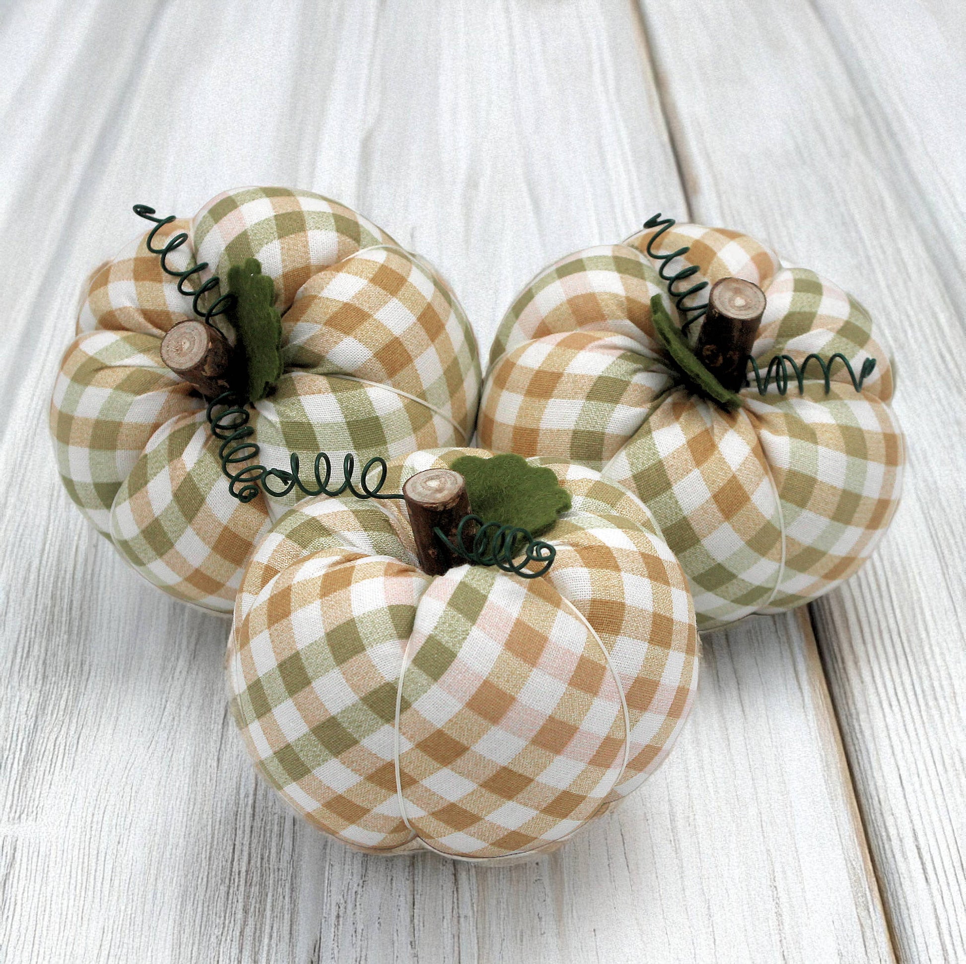 Three fabric pumpkins on a wooden surface