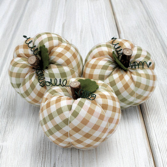 Three fabric pumpkins on a wooden surface