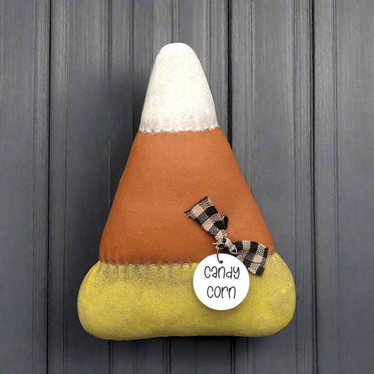 Distressed candy corn bowl filler with a tag on a wooden background