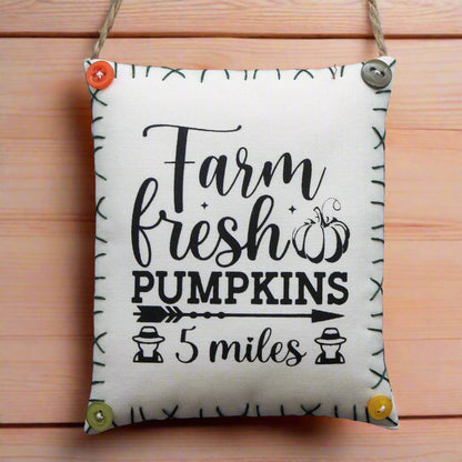 Decorative sign with 'Farm fresh pumpkins 5 miles' text on a wooden background