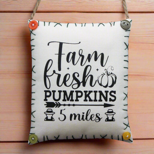 Decorative sign with 'Farm fresh pumpkins 5 miles' text on a wooden background