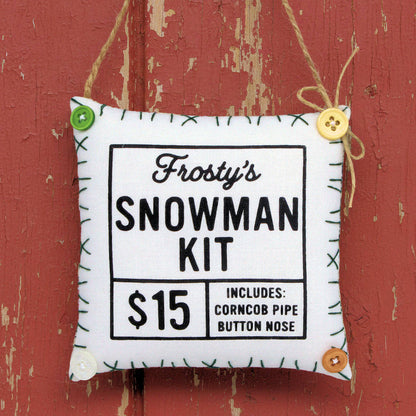 Fabric ornament labeled 'Frosty's Snowman Kit' with price and features on a gray background