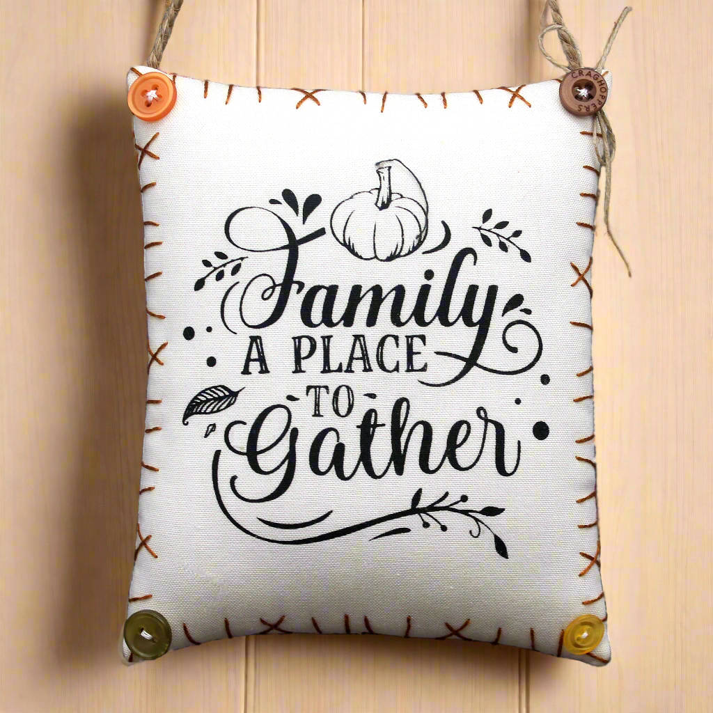 Decorative pillow with 'Family A Place To Gather' text and pumpkin design on a wooden background