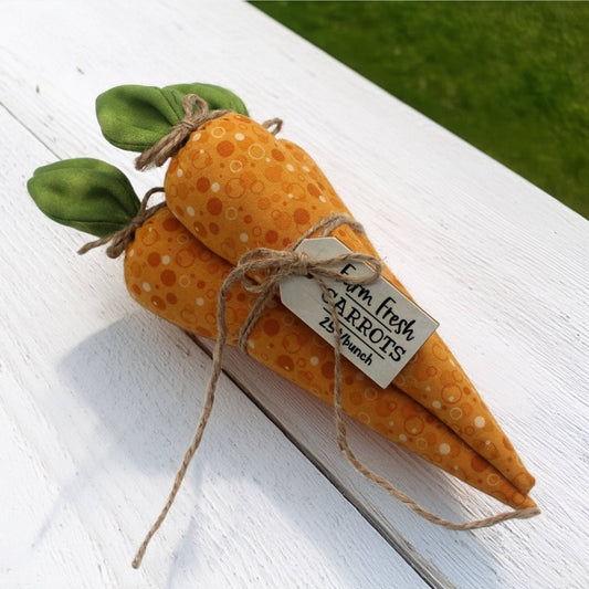 Fabric carrots with green leaves and a tag on a country table