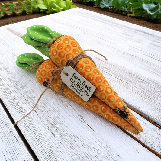 Fabric carrot shelf sitter on a wooden surface with a 'Farm Fresh Carrots' tag.