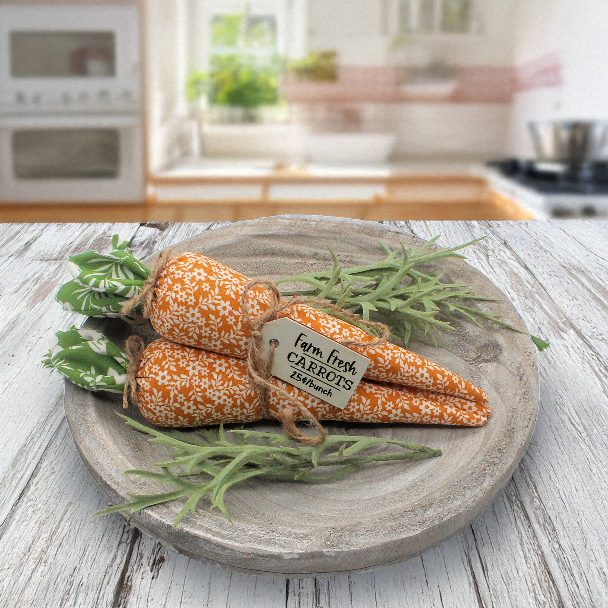 Decorative fabric carrots on a wooden plate with a kitchen in the background