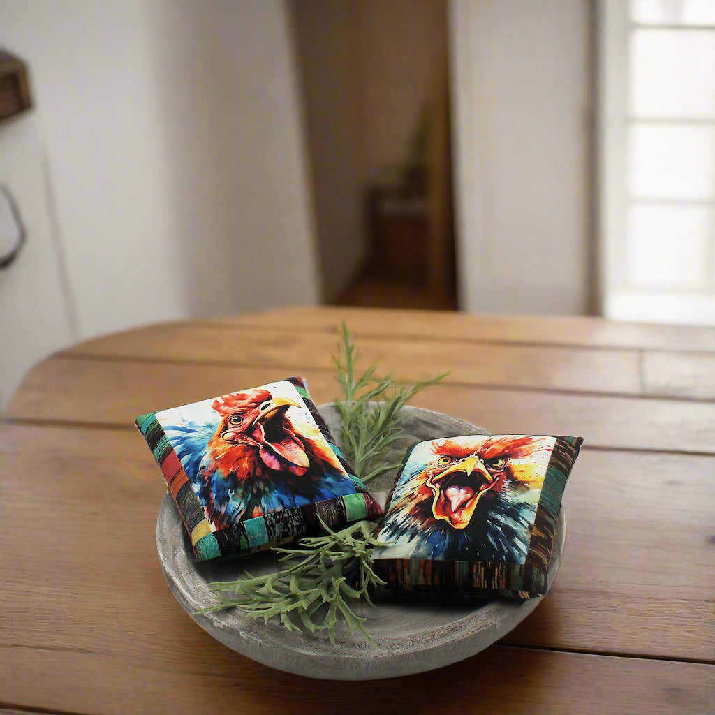 Two colorful rooster mini pillows in a wooden bowl on a table