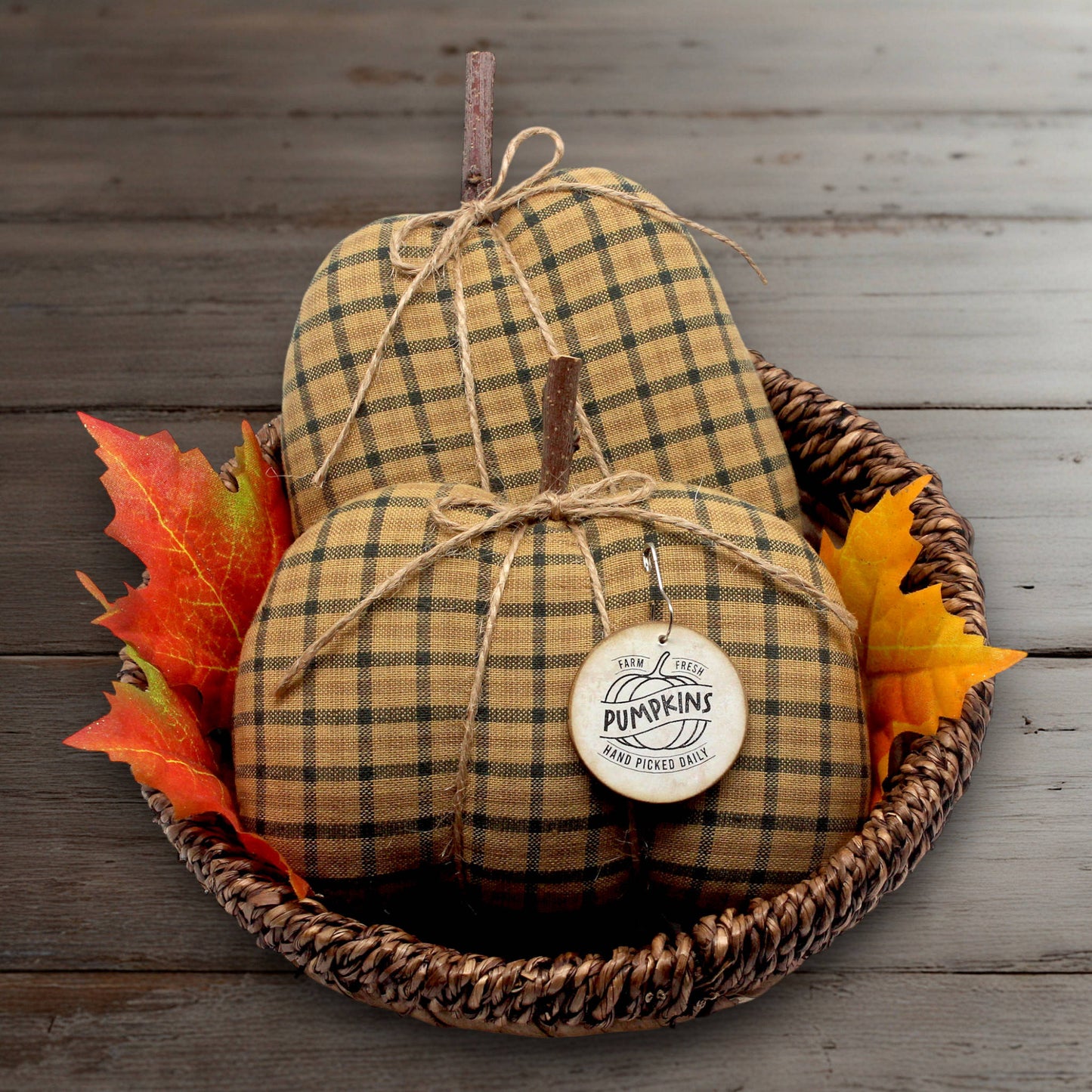 Set of two primitive handcrafted pumpkins from golden brown homespun fabric.  There's a wooden tag attached to one of the pumpkins and the ribs are formed by slender jute twine.