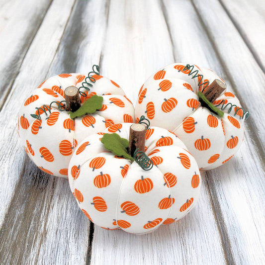 Set of three fabric pumpkin bowl fillers on a wooden table