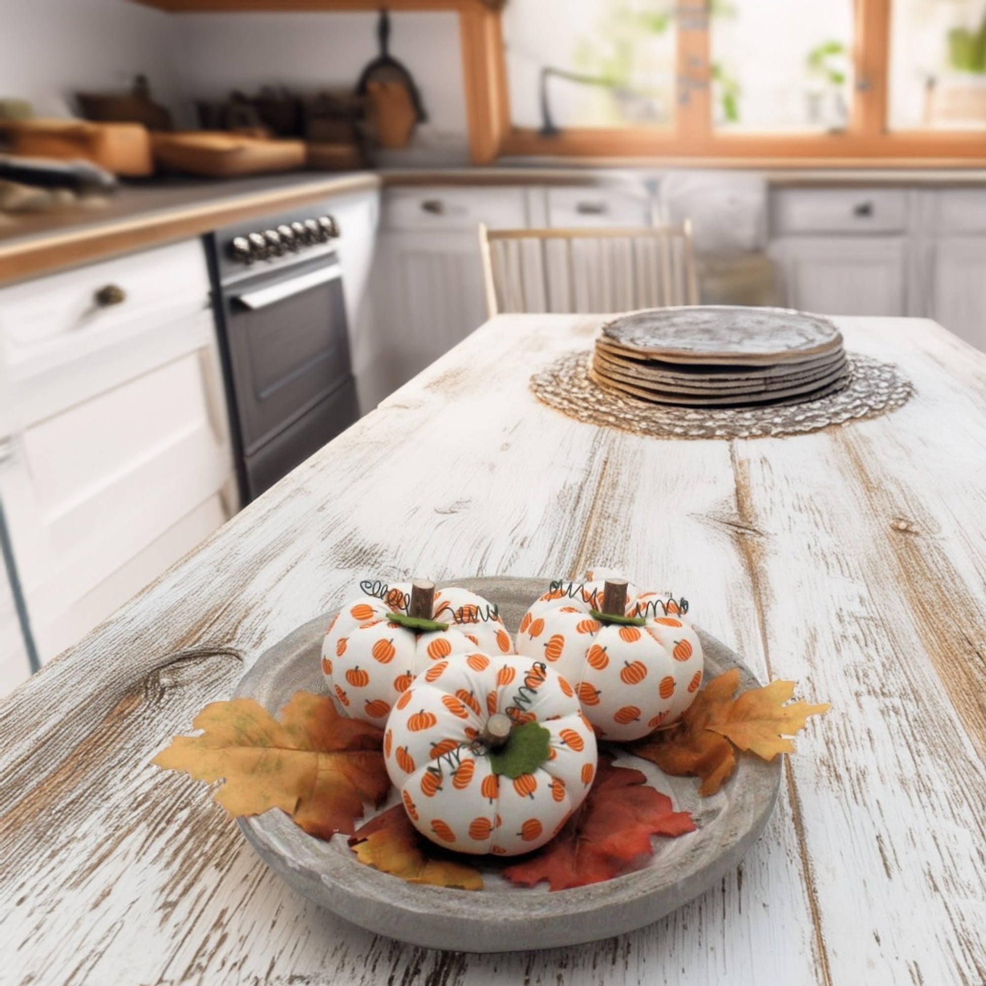 Decorative fabric pumpkins with orange patterns on a wooden table in a kitchen.