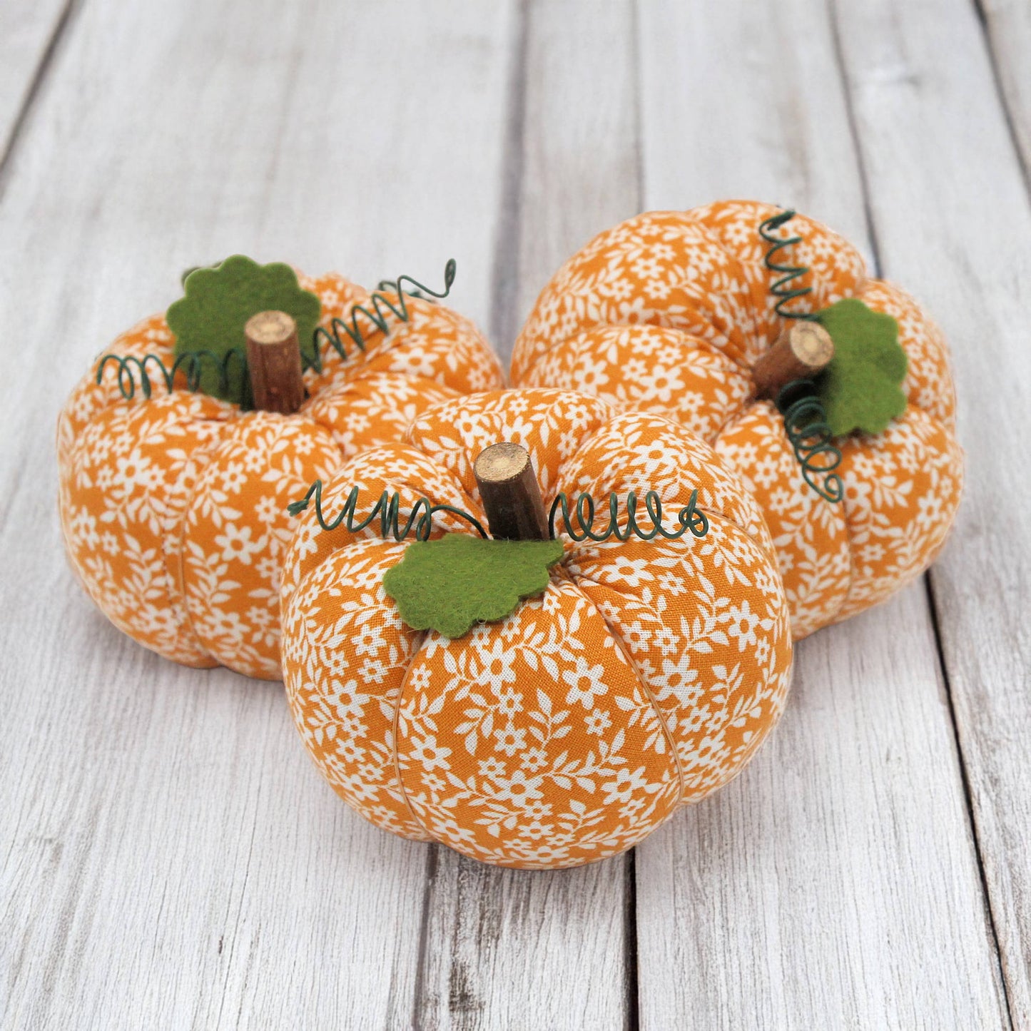 Three fabric pumpkin bowl fillers on a wooden table