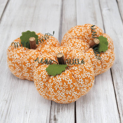 Three fabric pumpkin bowl fillers on a wooden table