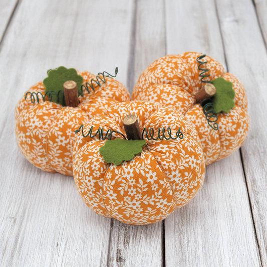 Three fabric pumpkin bowl fillers on a wooden table