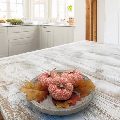 Decorative  fabric pumpkins with leaves on a wooden table in a kitchen.