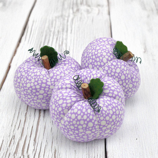 Purple fabric pumpkins with white polka dots on a wooden surface
