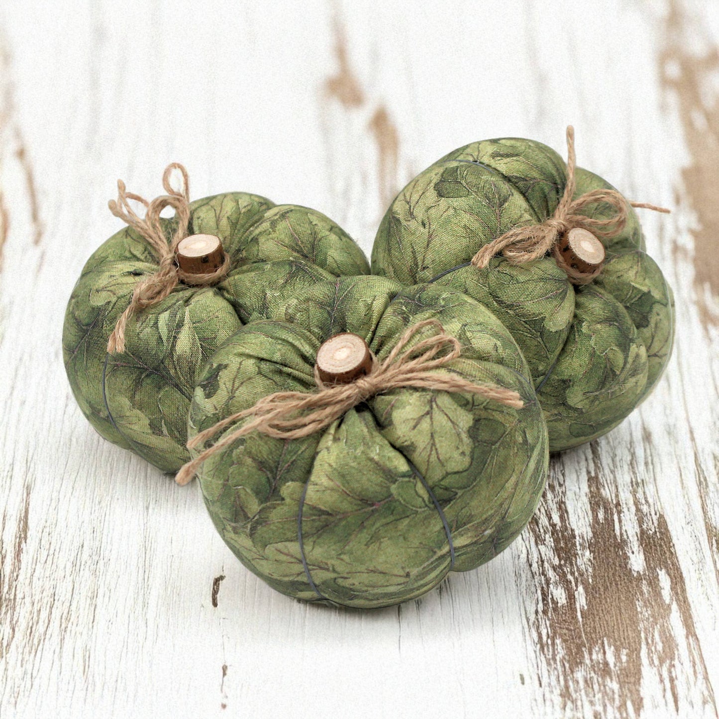 Three green fabric pumpkins with twine on a wooden surface