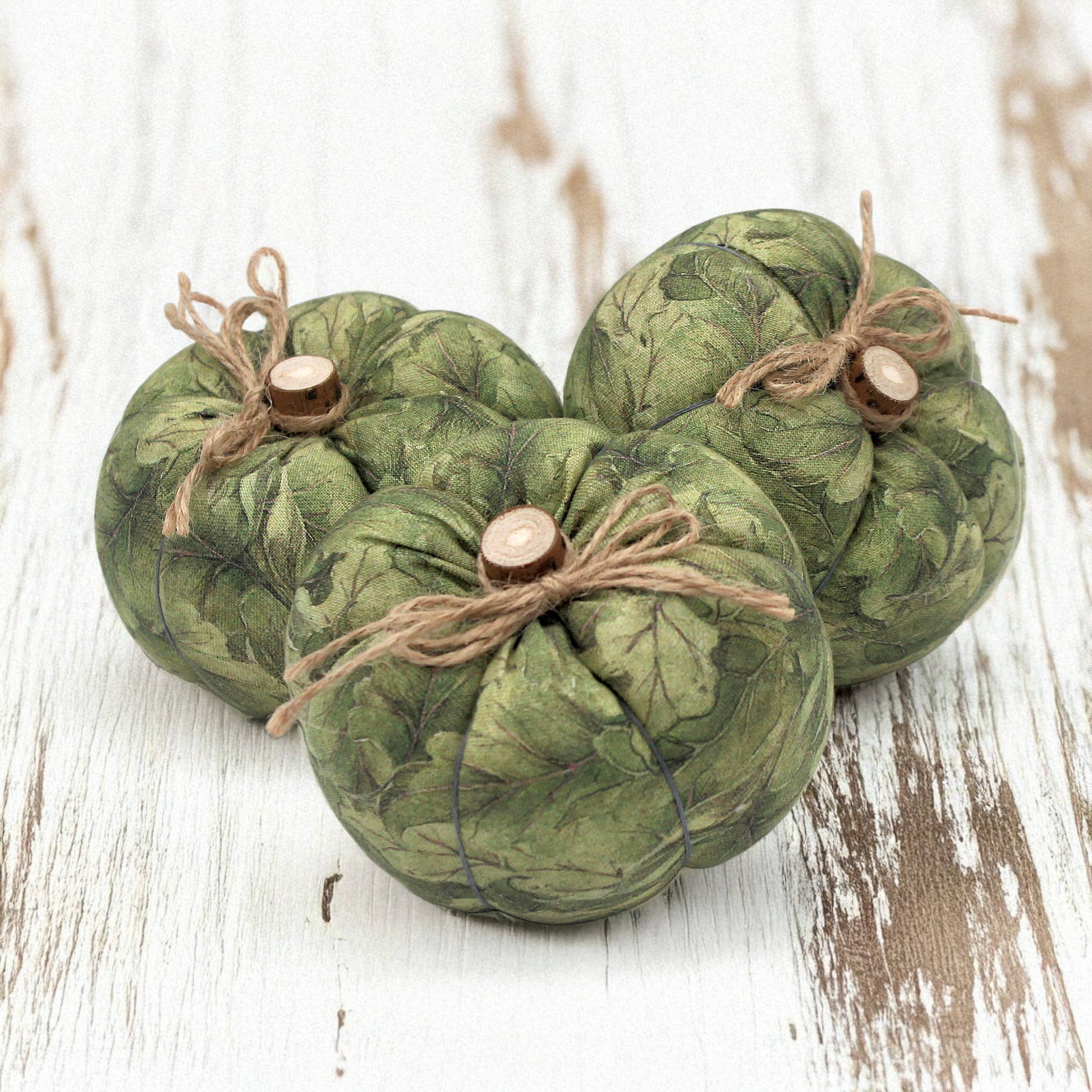 Three green fabric pumpkins with twine on a wooden surface