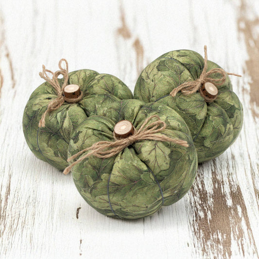 Three green fabric pumpkins with twine on a wooden surface