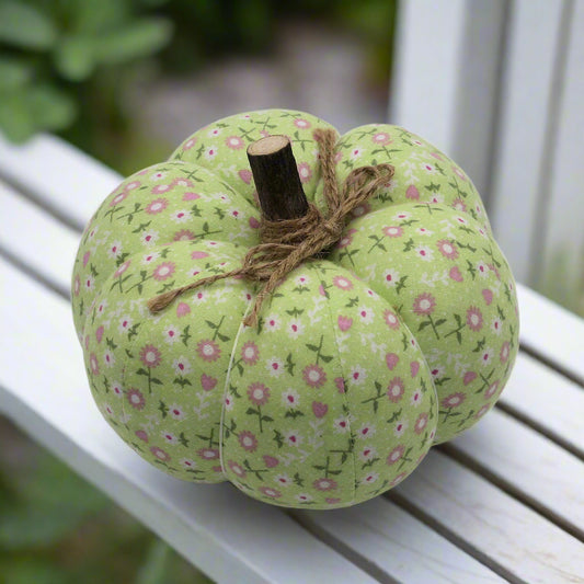 Decorative green pumpkin with floral pattern on a white surface