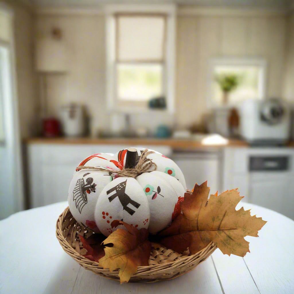 Decorative pumpkins with fall-themed designs in a basket on a kitchen counter.
