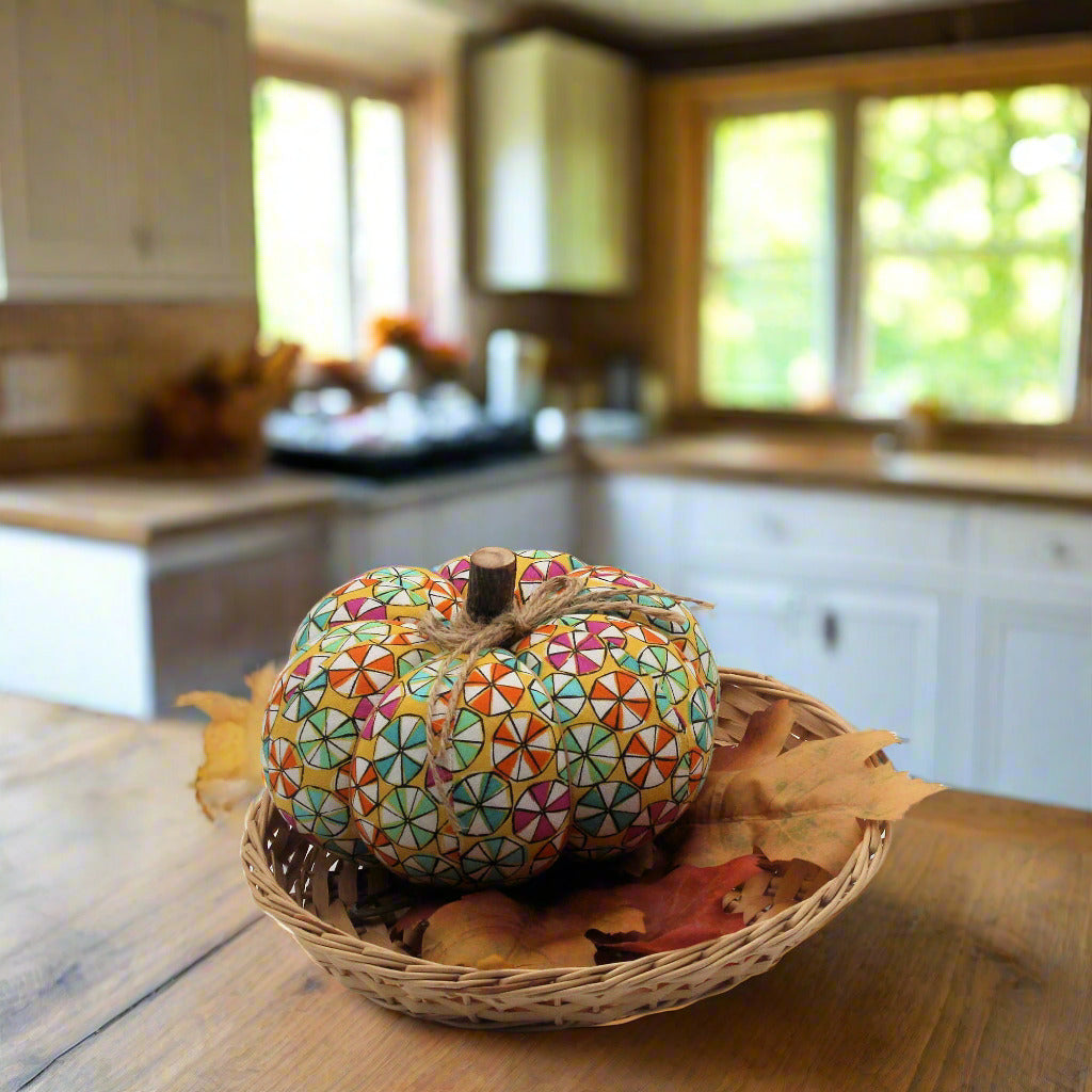 Decorative fabric pumpkin with a colorful candy wheel design in a country kitchen