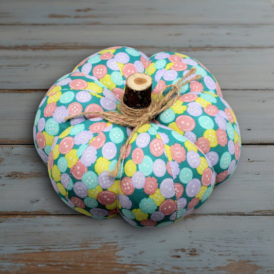 Decorative pumpkin with pastel button pattern on a wooden surface