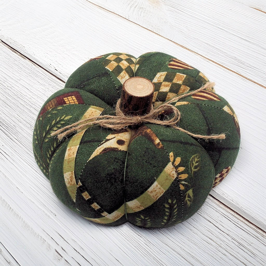 Decorative fabric pumpkin with a wooden stem on a white wooden surface