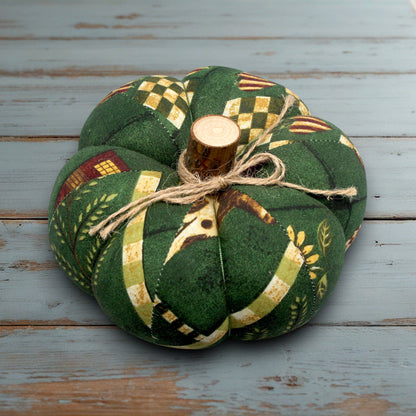 Decorative fabric pumpkin with a wooden stem on a white wooden surface