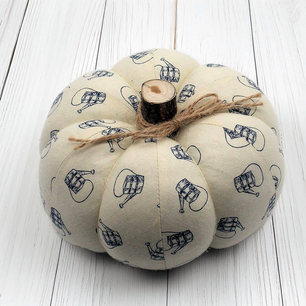 Fabric pumpkin with a watering can design on a white wooden surface