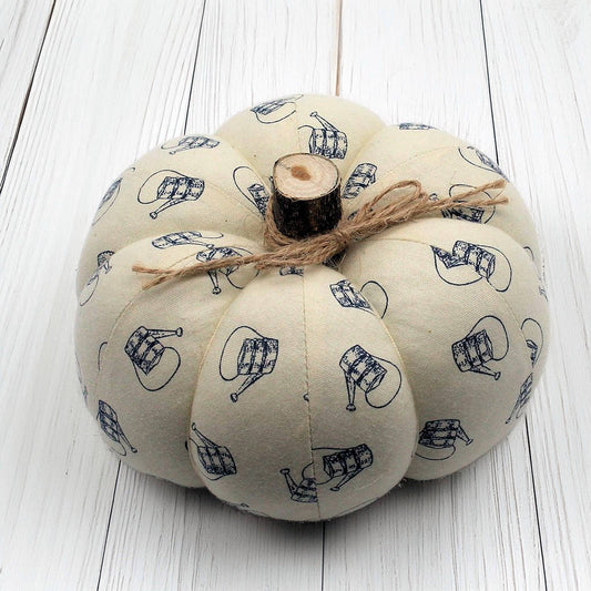 Fabric pumpkin with a watering can design on a white wooden surface