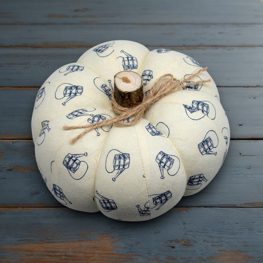 Fabric pumpkin with a watering can design on a white wooden surface